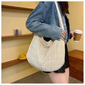 Macro detail of the white quilted texture and soft padded fabric on this large hobo bag