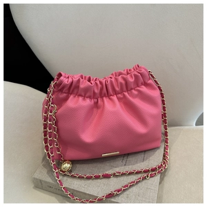 Détail du sac à main froncé rose montrant le cuir grainé et la bandoulière chaîne dorée
