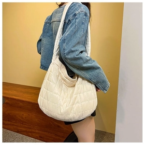 Detailed view of cream-colored quilted tote bag on model showing soft puffer texture
