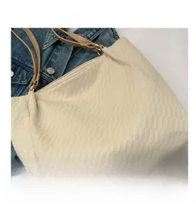 Close-up of cream checkerboard tote bag with adjustable brown strap and woven texture