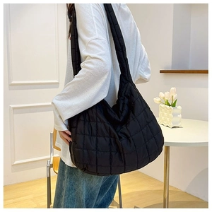 Detail view of a large black quilted tote bag with fluffy texture on a female model