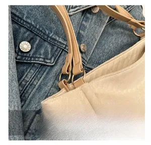 Detail view of the metal buckle and textured fabric on this beige canvas tote bag