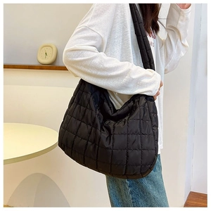Close-up of black quilted puffer tote bag with large square stitching and soft texture
