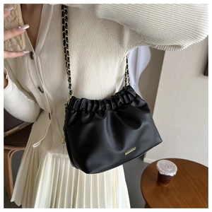 Détail du sac à chaîne en cuir grainé noir avec plis nuages et finitions dorées chic