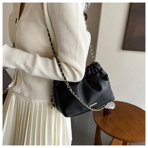 Détail du sac en cuir noir grainé avec une chaîne dorée élégante et fermeture à cordon