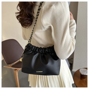 Détail du sac seau noir plissé avec bandoulière chaîne dorée et finitions métal