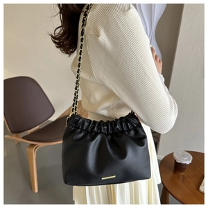 Détail du sac sous le bras plissé noir avec chaîne dorée et texture grainée lychee
