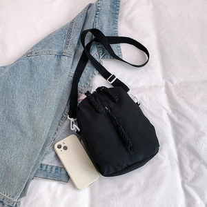 Minimalist black nylon crossbody bag with vertical zipper and white buckle accents