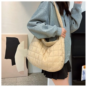 Detail of beige quilted hobo bag featuring square stitching and padded shoulder strap