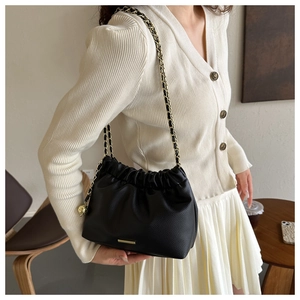 Détail du sac plissé noir avec texture grainée et bandoulière en chaîne dorée