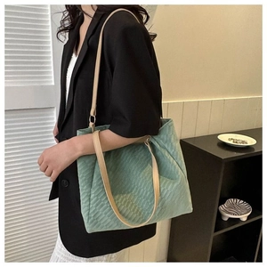 Detail view of mint green quilted tote bag with soft texture and leather straps
