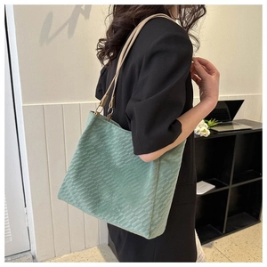 Detail of light green tote bag with quilted texture and slim brown shoulder strap on model