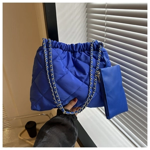 Detail van de blauwe gewatteerde bucket bag met kettingschakels en kleine portemonnee