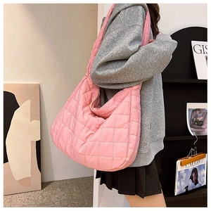 Detail of pink quilted tote bag showing square puffy texture on a female model