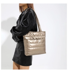 Macro detail of champagne gold quilted tote bag with metallic finish on model side