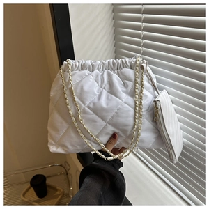 Detailopname van witte gewatteerde emmertas met gouden ketting en kleine opbergtas