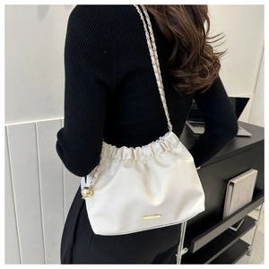 Détail du sac à bandoulière blanc en similicuir avec chaîne dorée et logo métallique