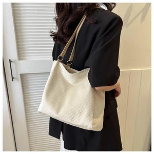 Minimalist ivory canvas tote bag with camel leather straps shown on a model's shoulder