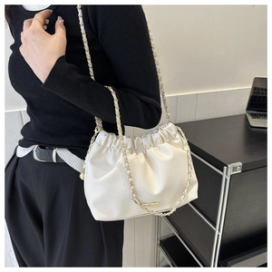 Détail du sac seau blanc plissé avec bandoulière chaîne dorée et cuir texturé
