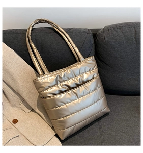 Macro detail of champagne quilted tote bag with padded nylon texture on grey sofa