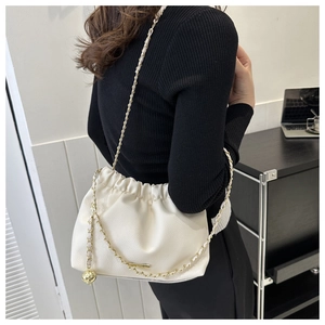 Détail du sac seau plissé blanc en cuir grainé avec bandoulière chaîne et boule d'or