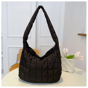 Close-up of black quilted puffer hobo bag with grid texture on a white round table