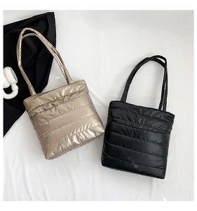 Detail view of quilted padded tote bags in metallic gold and black waterproof nylon