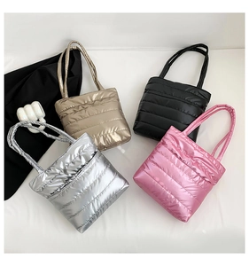 Flat lay of quilted down shoulder bags in silver, gold, black, and pink metallic finish