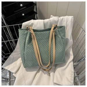 Detail of green woven tote bag with leather straps in a stylish metal basket