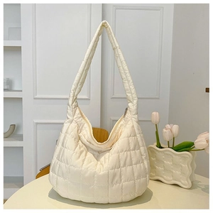 Detail of off-white quilted hobo bag with puffy texture and zip closure in a minimalist setting