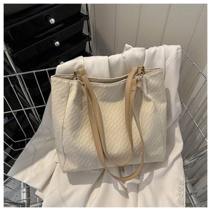 Close-up of geometric textured canvas tote bag with slim shoulder strap in a metal basket