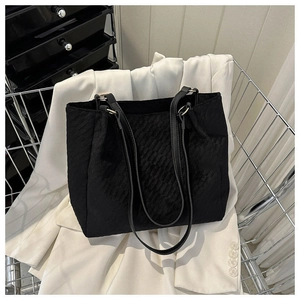 Detail shot of the black quilted canvas tote bag with textured finish in a stylish setting