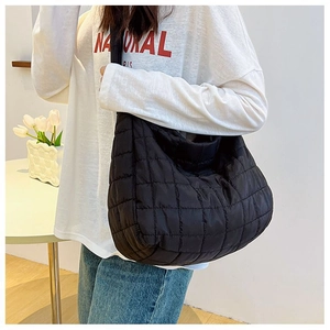 Detail of black quilted puffer tote bag showing padded nylon texture and large capacity
