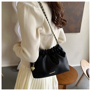 Détail du sac plissé en cuir noir avec chaîne dorée et pendentif sphérique