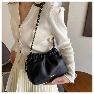 Détail du sac nuage noir plissé avec chaîne dorée et texture cuir grainé élégant