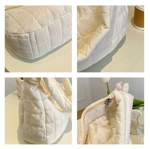 Detailed close-up of cream quilted down tote bag showing soft texture and zipper details