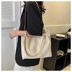 Close-up of cream canvas tote bag with diagonal texture and brown shoulder straps