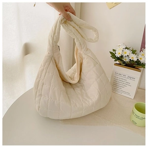 Detailed shot of beige quilted down tote bag with plush texture and zip closure