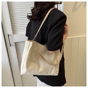 Detail of off-white tote bag showing woven texture and brown leather shoulder straps