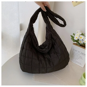 Detail of black quilted hobo bag featuring plush puffer texture and silver metal zipper