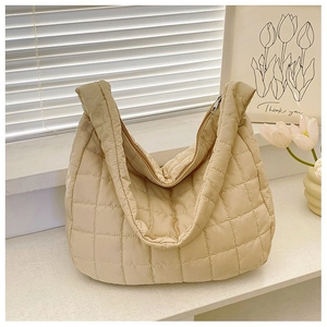 Detail of beige quilted puffer tote bag showing textured square padding and large zipper
