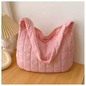 Close-up of pink quilted puffer bag with soft texture on a wooden table setup