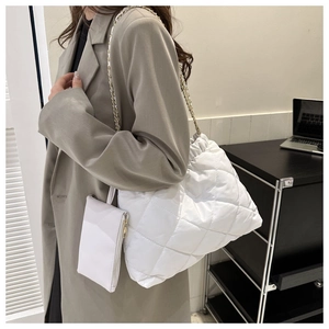 Detail van witte gewatteerde shopper met gouden ketting en bijpassend klein tasje
