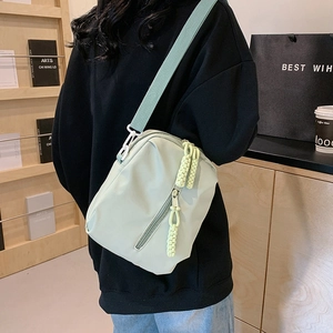 Bolso bandolera de nylon verde salvia con correa ajustable mostrado en un modelo