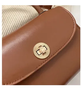 Detail of vintage brown leather handbag featuring a sunburst gold metal twist lock