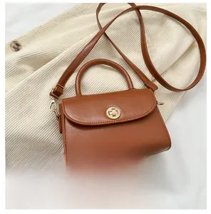 Miniature brown leather crossbody bag shown next to a smartphone for size comparison