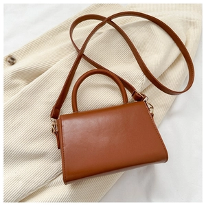Detail of caramel faux leather small square bag with top handle and gold-tone hardware