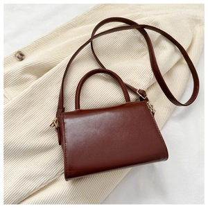 Detail of dark brown faux leather mini square bag with golden hardware and shoulder strap