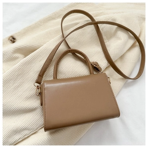 Macro detail of camel brown leather crossbody bag with structured handle and strap