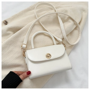 Detail of white PU leather mini crossbody bag with golden clasp on corduroy blazer